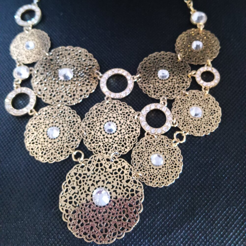 A preowned gold necklace designed in a mix of lacy look circles and rhinestones.